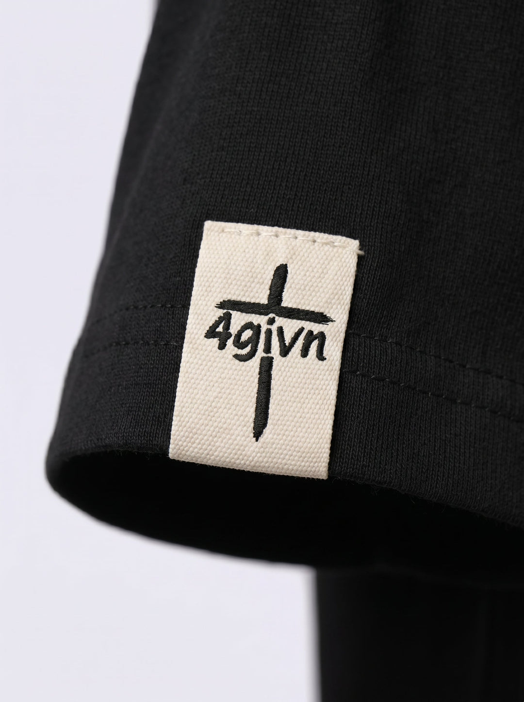 Detail van het 4GIVN mouwlabel op het zwarte Essential T-shirt