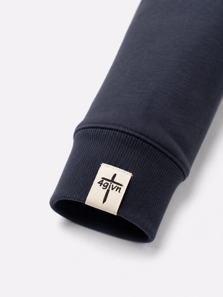 Detail van het 4GIVN mouwlabel op de Stand Firm Ink Blue sweater